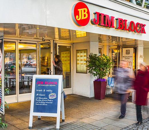Außenansicht des Jim Block Restaurants an der Kirchenallee mit Passanten und Aufsteller.