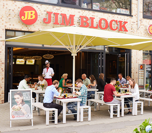 Außenbereich des Jim Block Restaurants in Altona mit Gästen unter großen Sonnenschirmen.