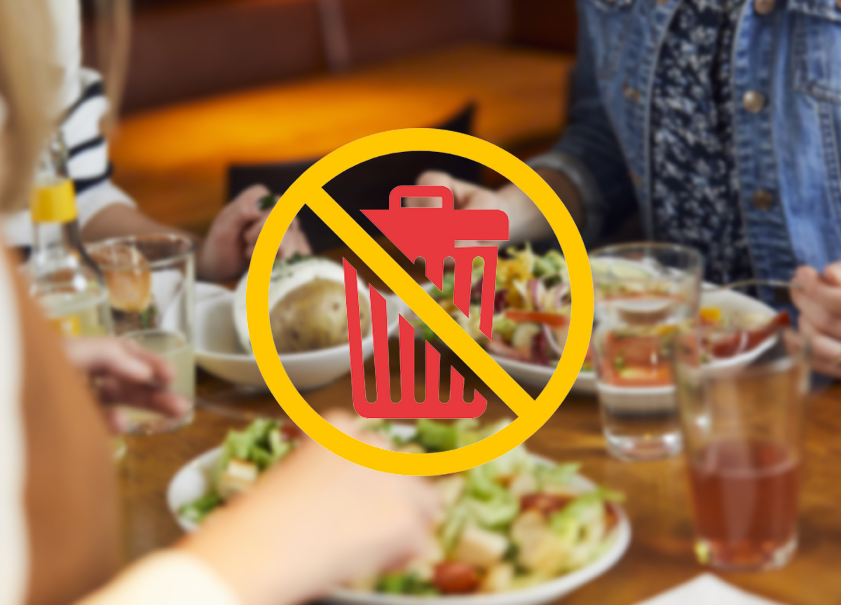 Symbol gegen Lebensmittelverschwendung über einem gedeckten Tisch mit Salat und Getränken.