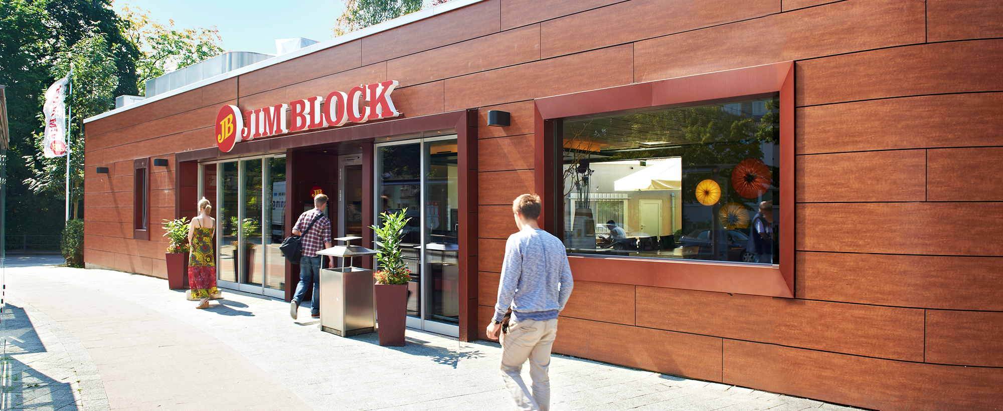 Außenansicht des Jim Block Restaurants in Othmarschen Außenansicht des Jim Block Restaurants in Othmarschen mit Holzfassade und Gästen am Eingang.