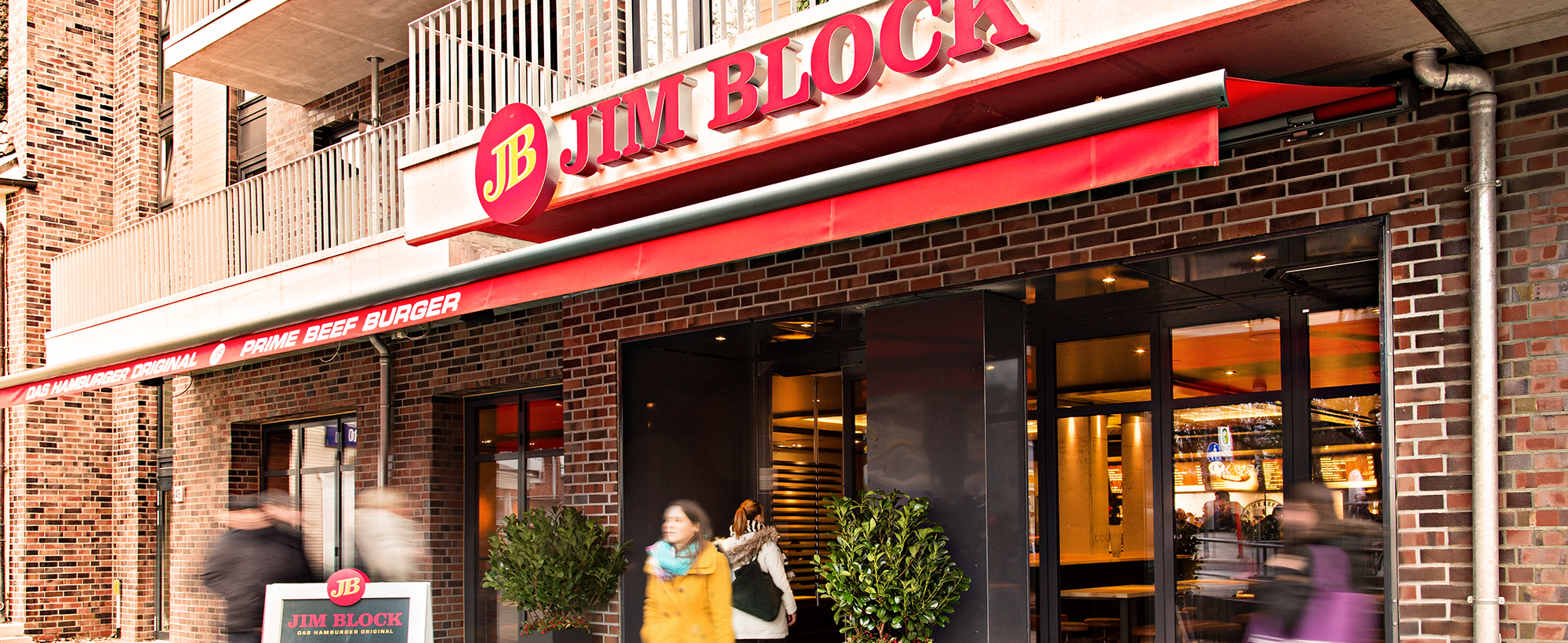 Außenansicht des Jim Block Restaurants in Langenhorn Außenansicht des Jim Block Restaurants in Langenhorn mit roter Markise und einladender Fassadengestaltung.