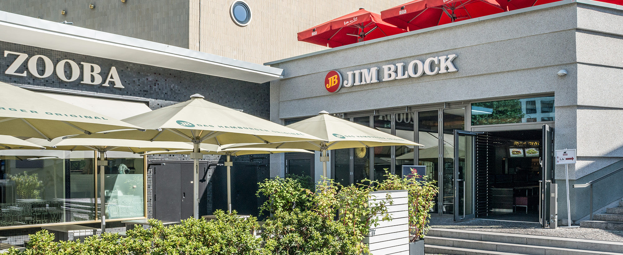 Außenbereich der Jim Block Filiale im Berliner Bikini-Haus Außenbereich der Jim Block Filiale im Berliner Bikini-Haus mit großen Sonnenschirmen und offener Eingangstür.